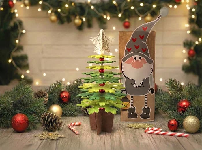Rétegekből összerakott karácsonyfa és manós papírtasak karácsonyi díszek között